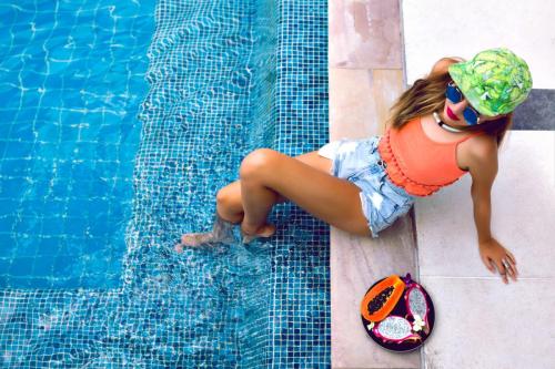 portrait-young-woman-posing-near-pool-with-tropical-fruits