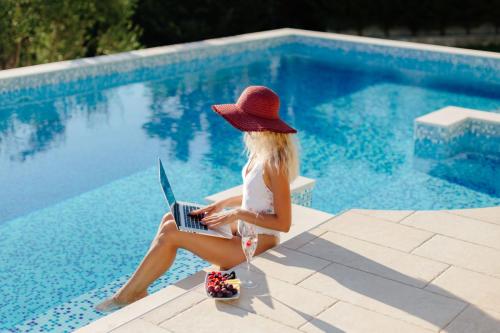 woman-using-laptop-near-swimming-pool